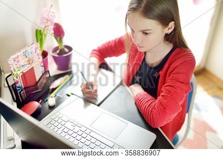 Preteen Schoolgirl Doing Her Homework With Laptop Computer At Home. Child Using Gadgets To Study. On