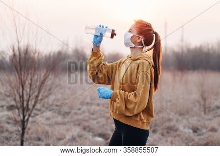 Covid-19 Pandemic Coronavirus Girl In Mask And Blue Gloves With A Bottle Of Water Trying To Drink Wa