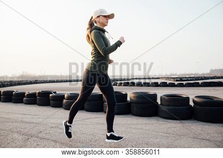 Morning Run Of A Young Girl On The Street In Black Leggings And Sneakers