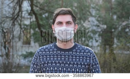 Young Man In White Medical Mask On The Street In The Period Of The Pandenic. Guy Take Off The Mask F