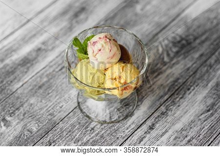 Colored Balls Of Ice Cream In A Glass Cremant On Wooden Grey Background.