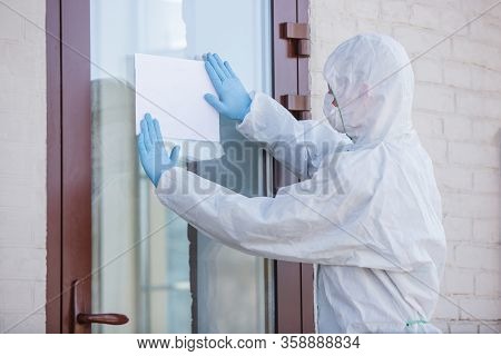 Coronavirus Pandemic. A Disinfector In A Protective Suit And Mask Making Warning Sign, Copyspace. Pr