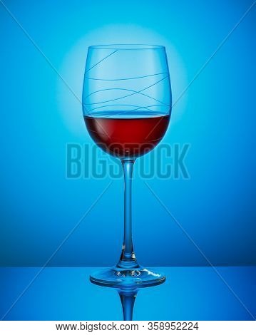 A Glass Of Red Wine On A Blue Background.