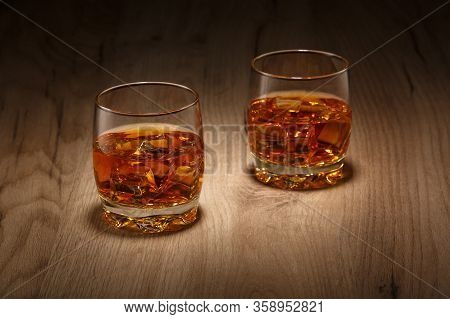 On The Wooden Table Are Two Glasses Of Whiskey On The Rocks.
