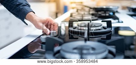 Male Hand Turning Switch Knob On Modern Gas Stove In Kitchen Showroom. Cooking Appliance In Domestic