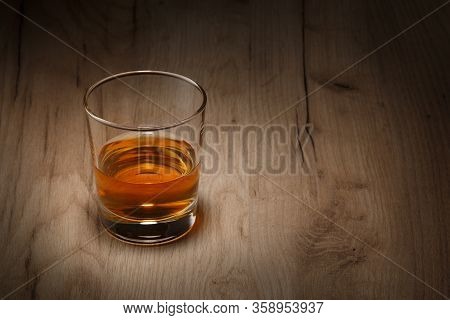A Glass Of Whiskey On A Wooden Table. Space For Text.