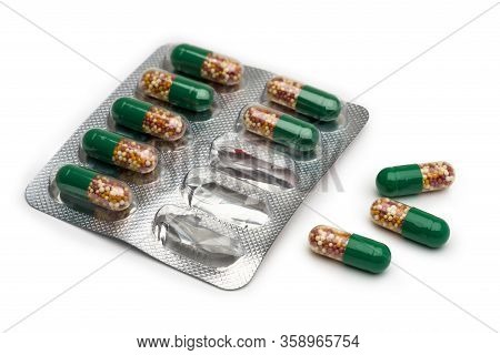 Isolate. Seven Capsules In Blister Packs And Three Unpacked. The Capsules Are Half Green And Transpa