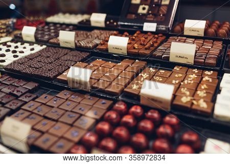 Assortment Of Chocolate Candies Desserts On Cafe Showcase. Variety Of Sweets With Different Flavours