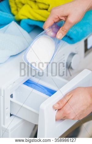 Washing Powder Detergent And Measuring Cup Pouring Into Machine. Household Duties, Clothes Laundry O