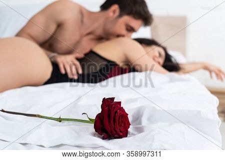 Selective Focus Of Red Rose Near Passionate Couple On Bed