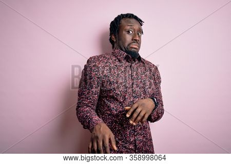 Young handsome african american man wearing casual shirt standing over pink background disgusted expression, displeased and fearful doing disgust face because aversion reaction.