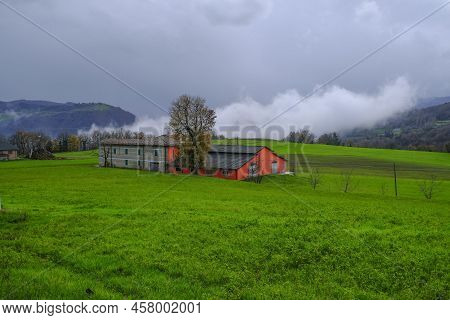 Red Farmhouse Across The Foggy Mountains And Green Hills. Italy, Appenino, Emilia-romagna,