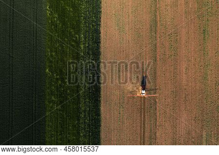 Aerial Shot Of Agricultural Tractor With Crop Sprayer Attached Spraying Herbicide Chemical Over Corn