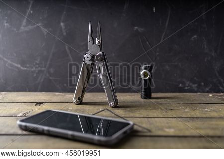 Pocket Folding Pliers And Compact Flashlight. Pocket Tools And Smartphone. Front View.