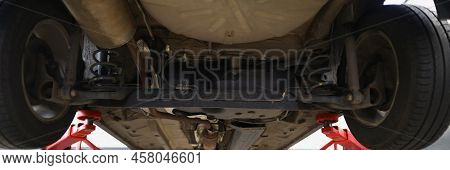 Close-up Of Car Lifted In Maintenance Service To Check Condition, Undercarriage Of Automobile. Botto