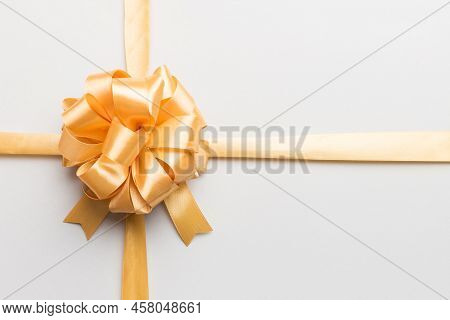 Top View Of Gold Ribbon Rolled And Yellowbow Isolated On Colored Background. Flat Lay With Copy Spac