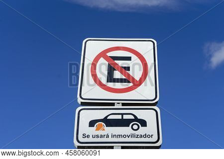 Parking Ban Sign With Spanish-language Wheel Block, Against Blue Sky