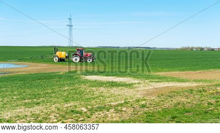A Tractor Sprays A Field Of Crops With Glyphosphate To Remove Weeds. Fertilization Of Crops With Min