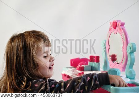 Pretty Little Girl Playing With Cosmetics Near Dressing Table In The Room. 2 Year Old.