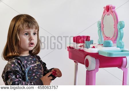 Cute Little Girl Painting Her Nails. Pretty Little Girl Playing With Cosmetics Near Dressing Table I