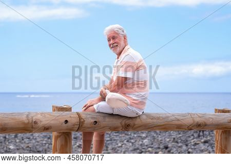 Portrait Of Relaxed Caucasian Bearded Man With Hat Sitting At The Beach Looking Away While Enjoying 