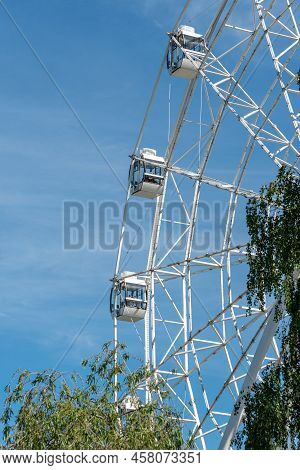 Ferris Wheel With White Covered Booths. The Attraction Is To Ride In A Circle. Part Of The Ferris Wh