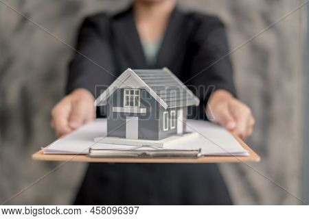 Home Insurance Concept And Real Estate. Businesswoman Holding A House Model Working In Investment Ab