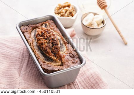 Chocolate Banana Bread With Walnuts In A Metallic Baking Mold And Ingredients On A Grey Neutral Back