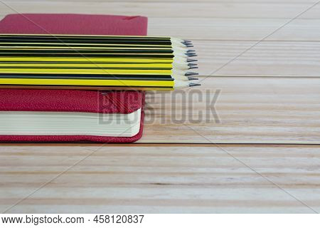 Wooden 2b Pencils Lying On Red Note Book On Wooden Desk. Copy Space.