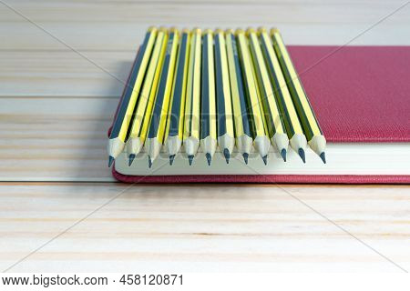 Wooden 2b Pencils Lying On Red Note Book On Wooden Desk. Copy Space.