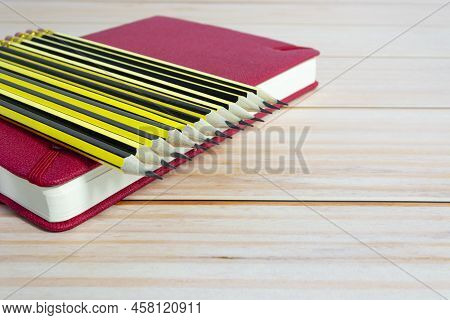 Wooden 2b Pencils Lying On Red Note Book On Wooden Desk. Copy Space.