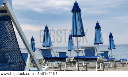 Of Deck Chairs And Umbrellas On The Sand Of The Beach, During A Summer Day