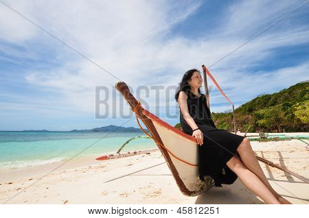 happy young girl sit on boat on white beach