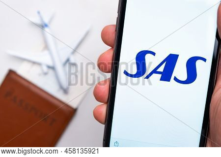 Sas Airline. A Mobile Phone And Sas Airline Application In Mans Hand. There Is A Passport And A Plan