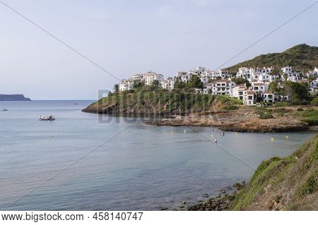Sunset In A Bay With Some White Houses On A Cliff And The Sun Filtering Through The Clouds, Some Boa