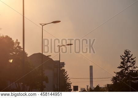 Selective Blur On Industrial Red Chimney Of A Factory Working And Releasing Toxic Fume And Smokes In