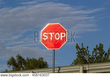 Red Stop Sign With Blue Sky And Clouds Background Of The Road