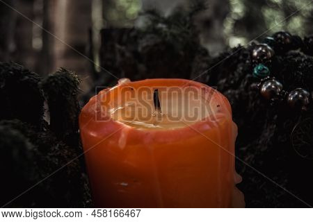 Red Extinguished Candle With Wax, A Symbol Of The Moon, An Amulet Lying On Moss On A Dark Natural Ba