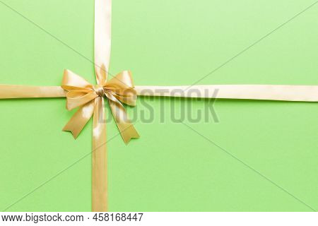 Top View Of Gold Ribbon Rolled And Yellowbow Isolated On Colored Background. Flat Lay With Copy Spac