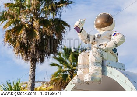 A Figurine Of An Astronaut In A Spacesuit Holding A Tube Of Food In His Hand Sits Against The Backdr