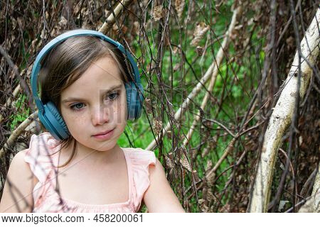 Young Beautiful Girl Fooling Around With A Branch And Wearing Headphones On Them To Listen To Music 