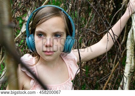 Young Beautiful Girl Fooling Around With A Branch And Wearing Headphones On Them To Listen To Music 