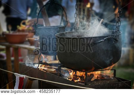 Large Iron Kettle Or Caldron With Steaming Stew Over Fire, Food For All On A Pristine Outdoor Feast,