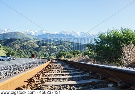 Kaikoura New Zealand - May 11 2022; Rusty Rail Tracks Running Along Kaikoura Coast With Man Walking 