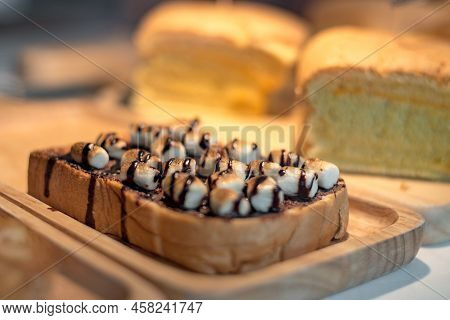 Sliced Toasted Bread With Marshmello Topping With Chocolate Sauce On Wooden Plate. Food And Drinks C