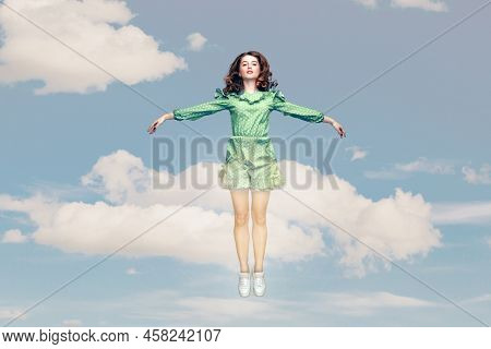 Full Length Happy Calm Pretty Girl In Ruffle Dress Levitating Hovering In Mid-air With Raised Hands 