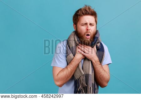 Portrait Of Bearded Man In Warm Scarf Coughing, Feeling Unwell With Sore Throat, High Temperature Fe
