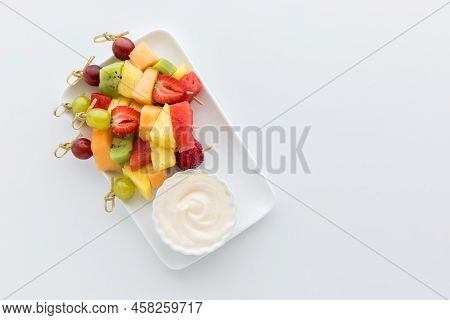 A Pile Of Fresh Fruit Skewers Served With Yogurt Dip. Copy Space To The Right.