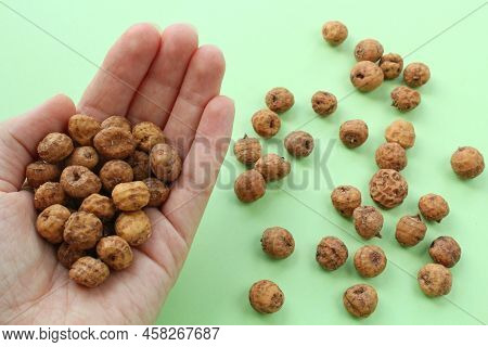 Chufa, Tigernut, Earth Almond In The Palm Of Outstretched Hand On Green Background. Healthy Food Con