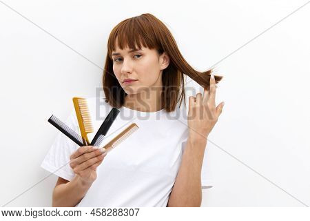A Sweet, Pleasant Woman With A Beautiful Hairstyle Holds A Lot Of Different Combs In One Hand, And P